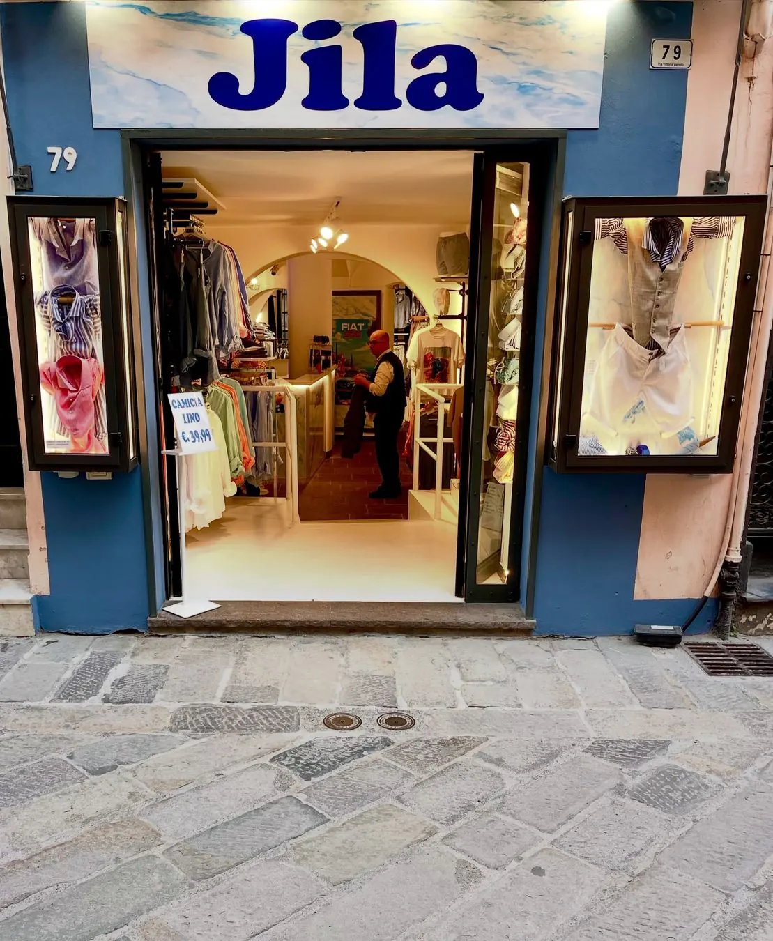 Vetrina e ingresso del negozio Jila in Via Vittorio Veneto 79 ad Alassio, illuminato di sera